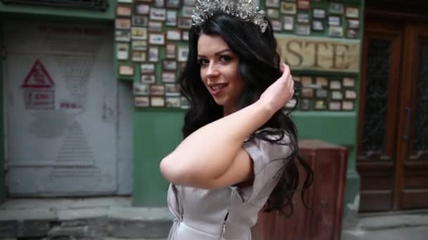 Brunette miss, in gray dress, slender legs, bright makeup, crown on head, posing — Stock Video