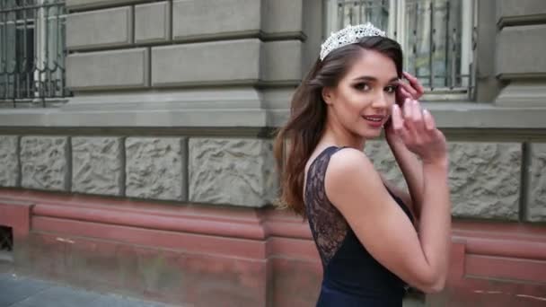 Girl brunette in dark blue long dress with lace, with a crown, posing for camera — Stock Video