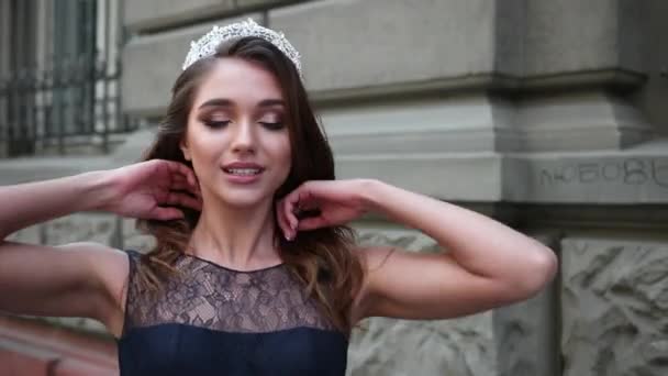 Meisje brunette in donker blauwe lange jurk met kant, met een kroon, poseren voor camera — Stockvideo