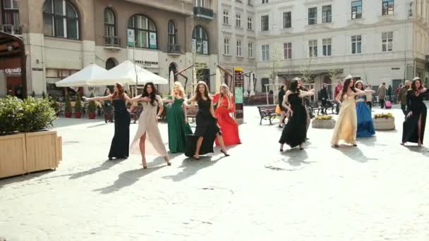 Πολλά όμορφα κορίτσια ντυμένοι με φορέματα και κορώνες χορεύοντας στο δρόμο — Αρχείο Βίντεο