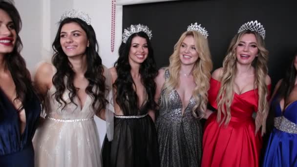 Wiele dziewczyn w wykwintnych sukienkach, z fryzurami i jasnym makijażu, z koronami — Wideo stockowe