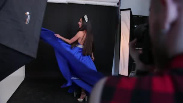 Sessão de fotos no estúdio, uma menina morena em um vestido azul, com decote profundo — Vídeo de Stock