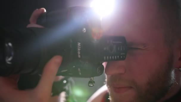 Homem fotógrafo tira fotos com uma câmera profissional, no estúdio — Vídeo de Stock