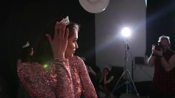 Ragazza dai capelli castani in abito rosa lucido, con una corona, un servizio fotografico in Studio — Video Stock