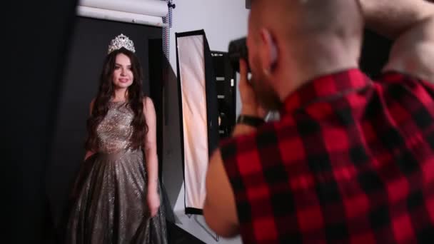 Fotógrafo fotografiando modelo chica, morena, en un vestido gris, en el estudio — Vídeos de Stock