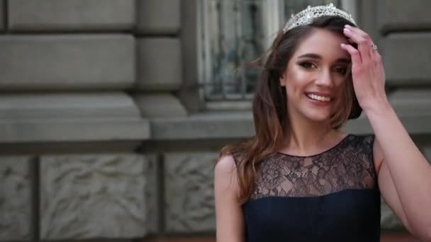 Girl brunette in dark blue long dress with lace, with a crown, posing for camera — Stock Video