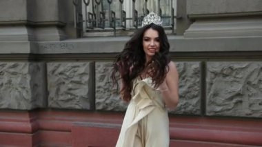 derin bir yaka ile hafif bir elbise esmer kız, bir taç ile, poz