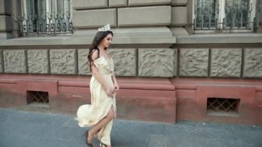 derin bir yaka ile hafif bir elbise esmer kız, bir taç ile, poz