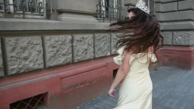 derin bir yaka ile hafif bir elbise esmer kız, bir taç ile, poz