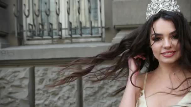 Fille modèle brunette dans une robe légère, avec une couronne, séance photo dans la rue — Video