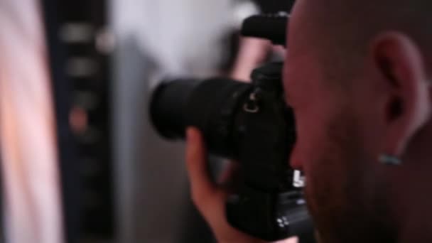 Fotógrafo hombre toma fotos con una cámara profesional, en el estudio — Vídeos de Stock