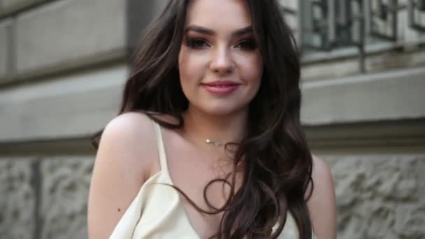 Meisje model brunette in een lichte jurk, met een kroon, fotoshoot op straat — Stockvideo