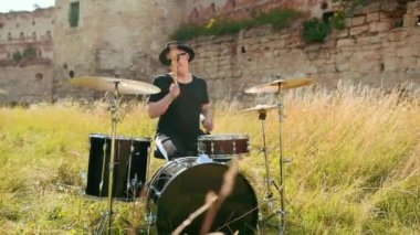 müzisyen davulcu siyah giysiler, şapka giymiş, davul seti ve ziller çalma