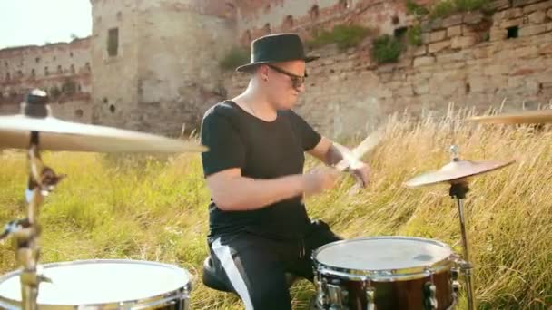 Музичний барабанщик, одягнений в чорний одяг, капелюх, грає на барабанному наборі і цимбалах — стокове відео