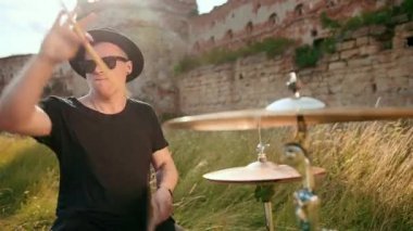 müzisyen davulcu siyah giysiler, şapka giymiş, davul seti ve ziller çalma