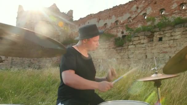 Drummer speelt de drum set en bekkens op straat, in de buurt van het vernietigde gebouw — Stockvideo