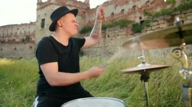 davulcu, davul seti ve ziller çalan, yıkılmış bir binanın yakınında sokakta