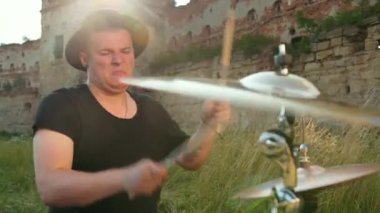 davulcu, davul seti ve ziller çalan, yıkılmış bir binanın yakınında sokakta