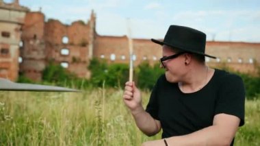 davulcu, davul seti ve ziller çalan, yıkılmış bir binanın yakınında sokakta