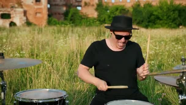 Drummer, playing drum set and cymbals, on street near a destroyed building — Stock Video