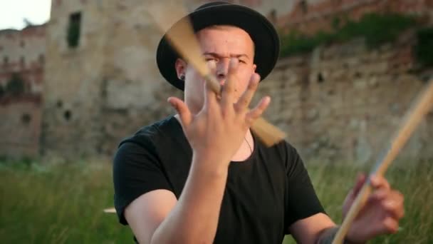 Profesjonalny perkusista, ubrany w czarną czapkę, skręty pałeczki, na ulicy — Wideo stockowe