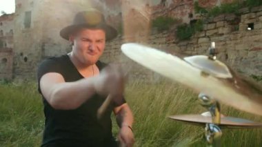 müzisyen davulcu siyah giysiler, şapka giymiş, davul seti ve ziller çalma