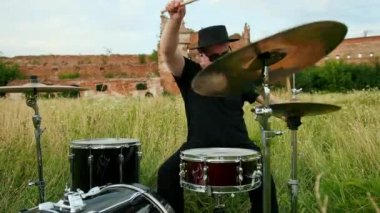 siyah şapka giymiş müzisyen davulcu, davul seti ve ziller, sokakta oynuyor