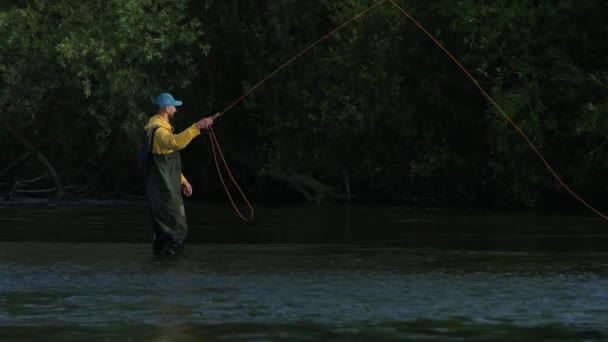 Homem pescador segurando uma vara de pesca, joga um flutuador, pesca no rio — Vídeo de Stock