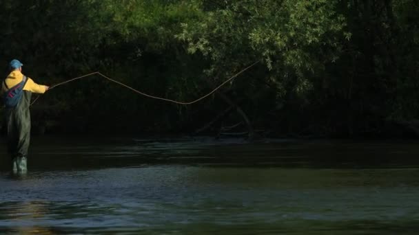 Man fiskare som innehar ett fiskespö, kastar en flottör, fiske i floden — Stockvideo