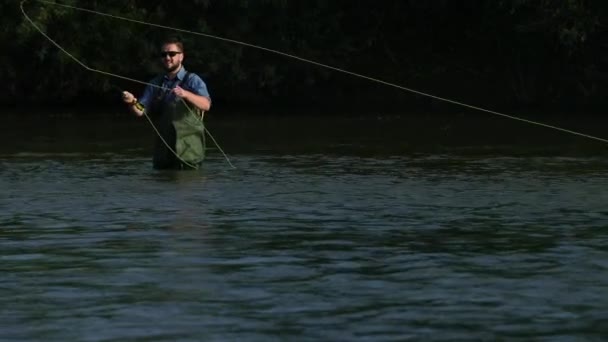 男子渔夫拿着钓鱼竿，扔一个浮子，在河里钓鱼 — 图库视频影像