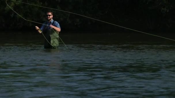 Homem pescador segurando uma vara de pesca, joga um flutuador, pesca no rio — Vídeo de Stock