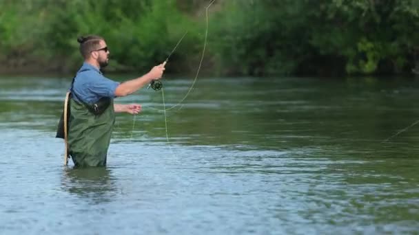 Pescador hombre sosteniendo una caña de pescar, lanza una carroza, pesca en el río — Vídeos de Stock