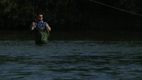 Homem pescador segurando uma vara de pesca, joga um flutuador, pesca no rio — Vídeo de Stock