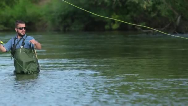 Pescador hombre sosteniendo una caña de pescar, lanza una carroza, pesca en el río — Vídeos de Stock