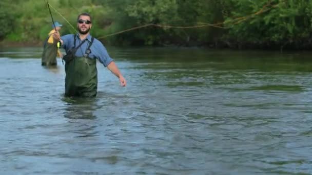 Pesca, dos hombres pescando en el río, de pie en el agua, una pequeña corriente — Vídeo de stock