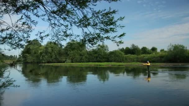 Uomo pescatore in possesso di una canna da pesca, getta un galleggiante, pesca nel fiume — Video Stock