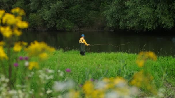 釣り竿を持った男漁師は、川で釣り、フロートを投げる — ストック動画