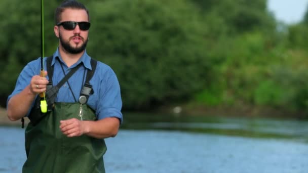 Man visser Holding een hengel, gooit een float, vissen in de rivier — Stockvideo