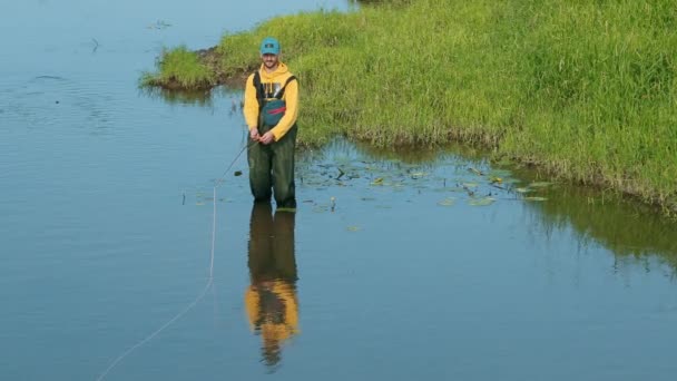 Man fiskare som innehar ett fiskespö, kastar en flottör, fiske i floden — Stockvideo