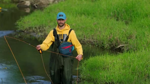 Чоловік рибалка тримає вудку, кидає поплавок, рибалка в річці — стокове відео