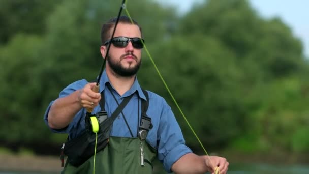 Homem pescador segurando uma vara de pesca, joga um flutuador, pesca no rio — Vídeo de Stock