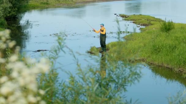 Homem pescador segurando uma vara de pesca, joga um flutuador, pesca no rio — Vídeo de Stock