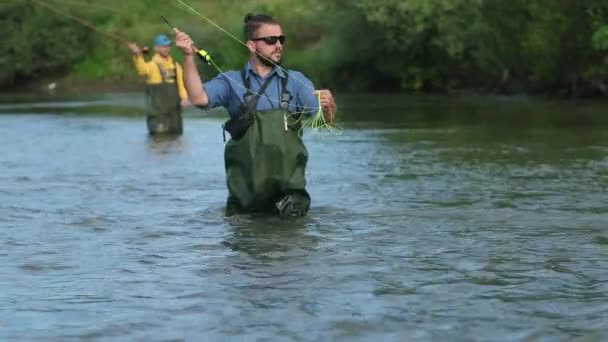 Pêche, deux hommes pêchant sur la rivière, debout dans l'eau, un petit courant — Video