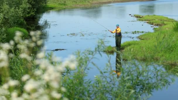 Man fiskare som innehar ett fiskespö, kastar en flottör, fiske i floden — Stockvideo