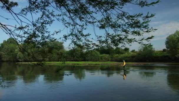 Uomo pescatore in possesso di una canna da pesca, getta un galleggiante, pesca nel fiume — Video Stock