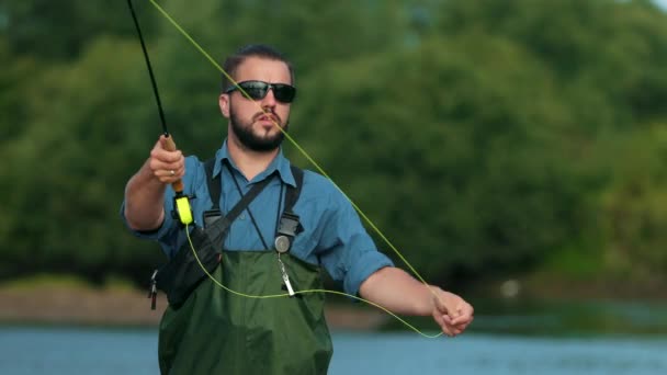 Man fiskare som innehar ett fiskespö, kastar en flottör, fiske i floden — Stockvideo