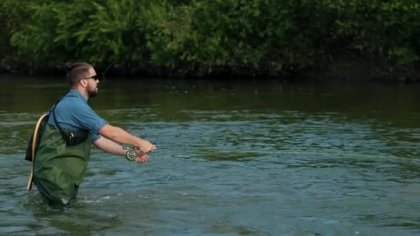 Homem pescador segurando uma vara de pesca, joga um flutuador, pesca no rio — Vídeo de Stock