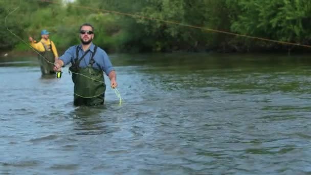 Angeln, zwei Männer angeln auf dem Fluss, im Wasser stehend, eine kleine Strömung — Stockvideo