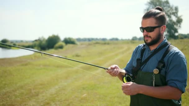 Hombre pescador, pesca, sosteniendo una caña de pescar, encadenando cebo, carrete giratorio — Vídeo de stock