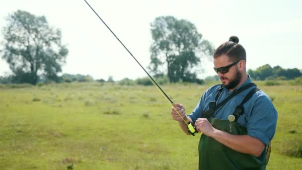 Homme pêcheur, pêche, tenir une canne à pêche, appât à cordes, bobine filante — Video